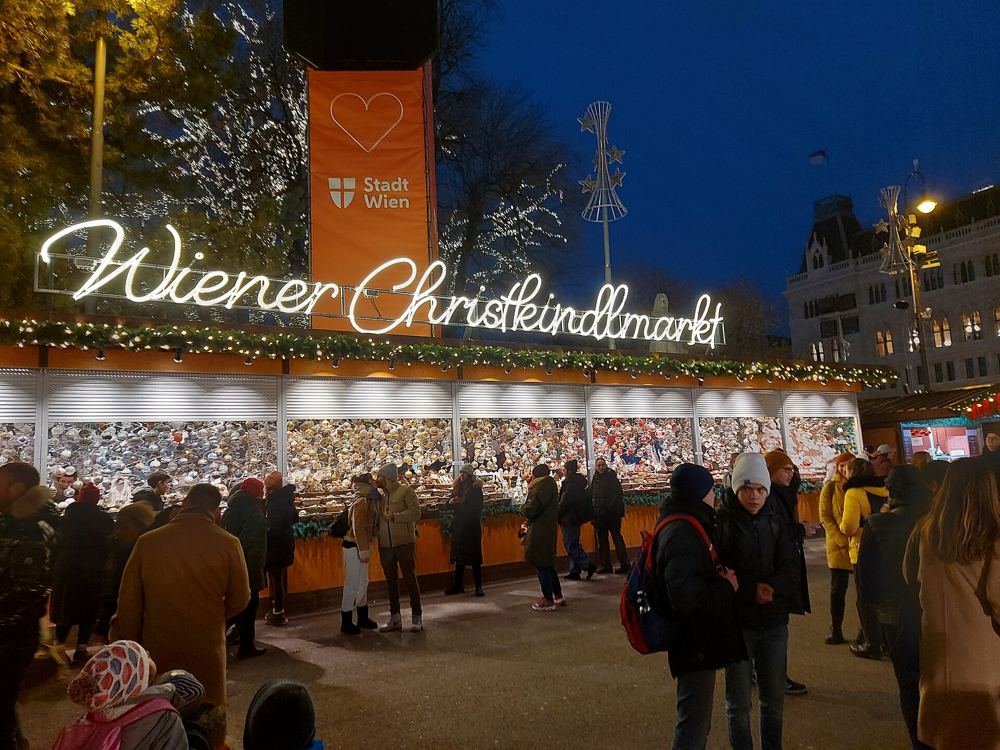 Wiener Christkindlmarkt sign and stalls on Rathausplatz at dusk